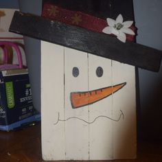 a wooden block with a snowman face painted on it's side and a flower in the center