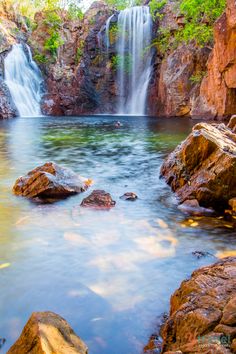 a large waterfall in the middle of a forest filled with lots of rocks and water