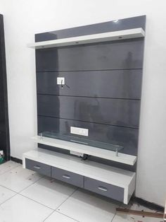 an entertainment center in the corner of a room with white tile flooring and gray cabinets