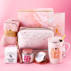 the contents of a pink cosmetic bag are displayed on a pink background with gold accents