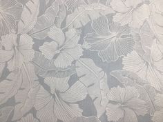 an upholstered fabric with white flowers and leaves on grey background, closeup