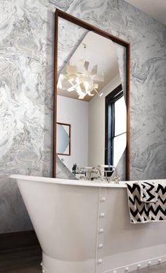 a white bath tub sitting under a bathroom mirror