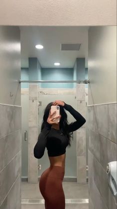 a woman taking a selfie in a bathroom with her cell phone up to her ear