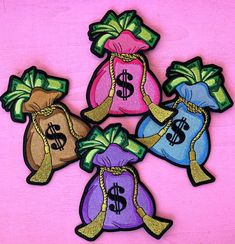 four bags filled with money sitting on top of a pink surface