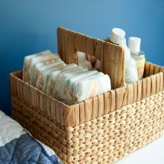 a wicker basket with soaps and lotion bottles in it on a bed