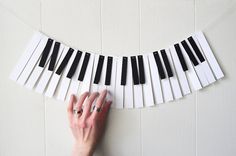 a string of black and white piano keys hanging from a wall in the shape of a garland