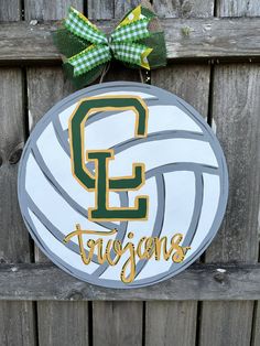 a sign with the word e and a volleyball on it hanging from a wooden fence