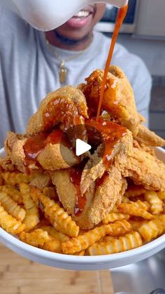 a person pouring sauce on fried food in a bowl