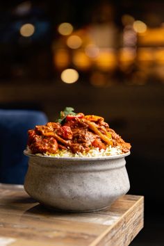 a bowl filled with food sitting on top of a wooden table