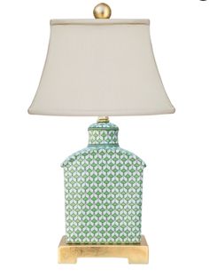 a table lamp with a green and white patterned jar on it, next to a gold base