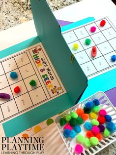 a paper board game with pom poms on it and a play time box