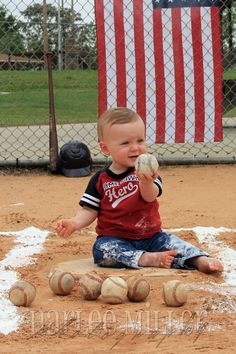 a little boy that is sitting in the dirt with some baseballs