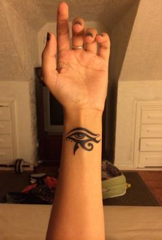 a woman's arm with an egyptian eye tattoo on her left wrist and hand