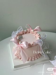 a pink cake decorated with bows and pearls