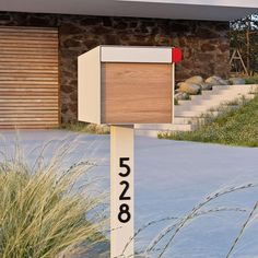 a mailbox in front of a house with numbers on it and grass next to it