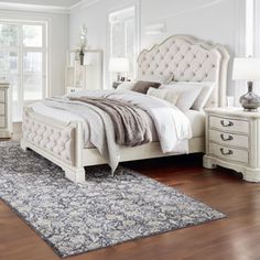 a white bed sitting on top of a wooden floor next to a dresser and mirror