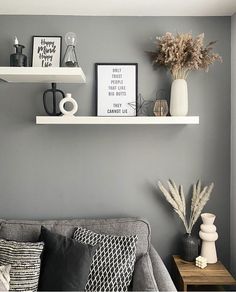 a living room filled with furniture and decor on top of white shelving units next to a gray wall