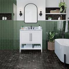 a bathroom with green tile walls and flooring next to a bathtub, sink and mirror