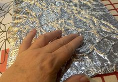 a hand is touching foil on a table