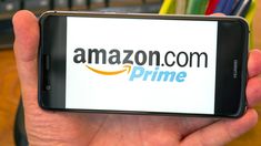 a person holding up a smart phone with the amazon com prime logo on it