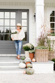 a woman standing on the steps with flowers in front of her and holding a basket