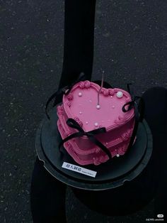 a pink heart shaped cake sitting on top of a black plate