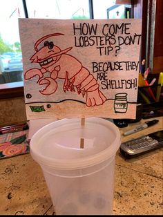 a plastic cup sitting on top of a counter next to a sign that says how come lobsters do it?