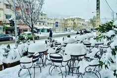 tables and chairs covered in snow on a city street