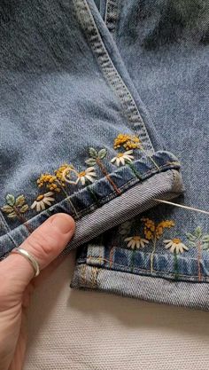 someone is stitching flowers on the back of their jean pants with a sewing needle