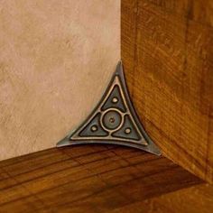 a triangle shaped metal object on top of a wooden table next to a white wall