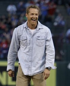 a man laughing while standing on top of a baseball field in front of a crowd