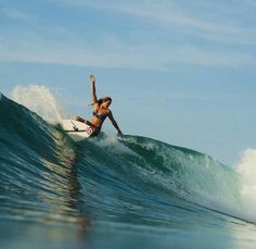 a woman riding a wave on top of a surfboard