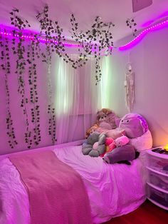 a bedroom with pink lighting and stuffed animals on the bed