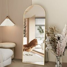 a large mirror sitting on top of a table next to a vase with flowers in it