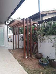 an outdoor patio area with potted plants on the side and a pergolated roof