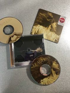 two cds sitting on top of a table next to each other, one has a disc in it