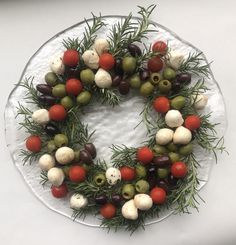 a wreath made out of olives, tomatoes and other vegetables on a platter