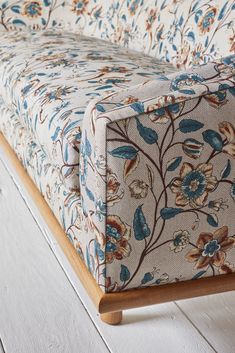 an upholstered couch with blue and orange flowers on it's back end