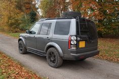 an suv parked on the side of a road in front of trees with leaves all over it