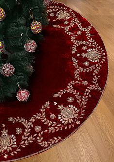 a christmas tree with ornaments on it in front of a red rug and wooden floor