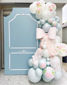 a bunch of balloons that are in front of a door with a bow on it