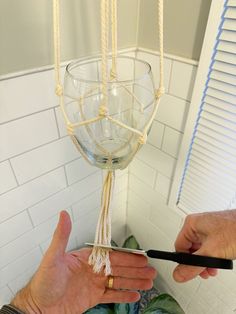 a person holding a wine glass in front of a candle holder that is hanging from the ceiling