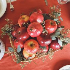 a basket filled with apples sitting on top of a table next to plates and utensils