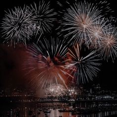 fireworks are lit up in the night sky over water