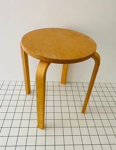 a small wooden table sitting on top of a white tiled floor next to a wall