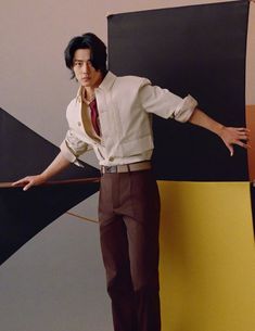 a man standing in front of a black and yellow wall with his hands on his hips