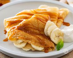 a white plate topped with pancakes covered in syrup and bananas