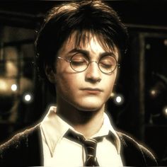 harry potter in glasses and a tie looking at the camera with his eyes wide open