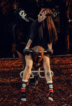 two people sitting on a bench in the woods with their faces painted white and black