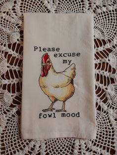 an embroidered tea towel with a chicken saying please excuse my fowl mood